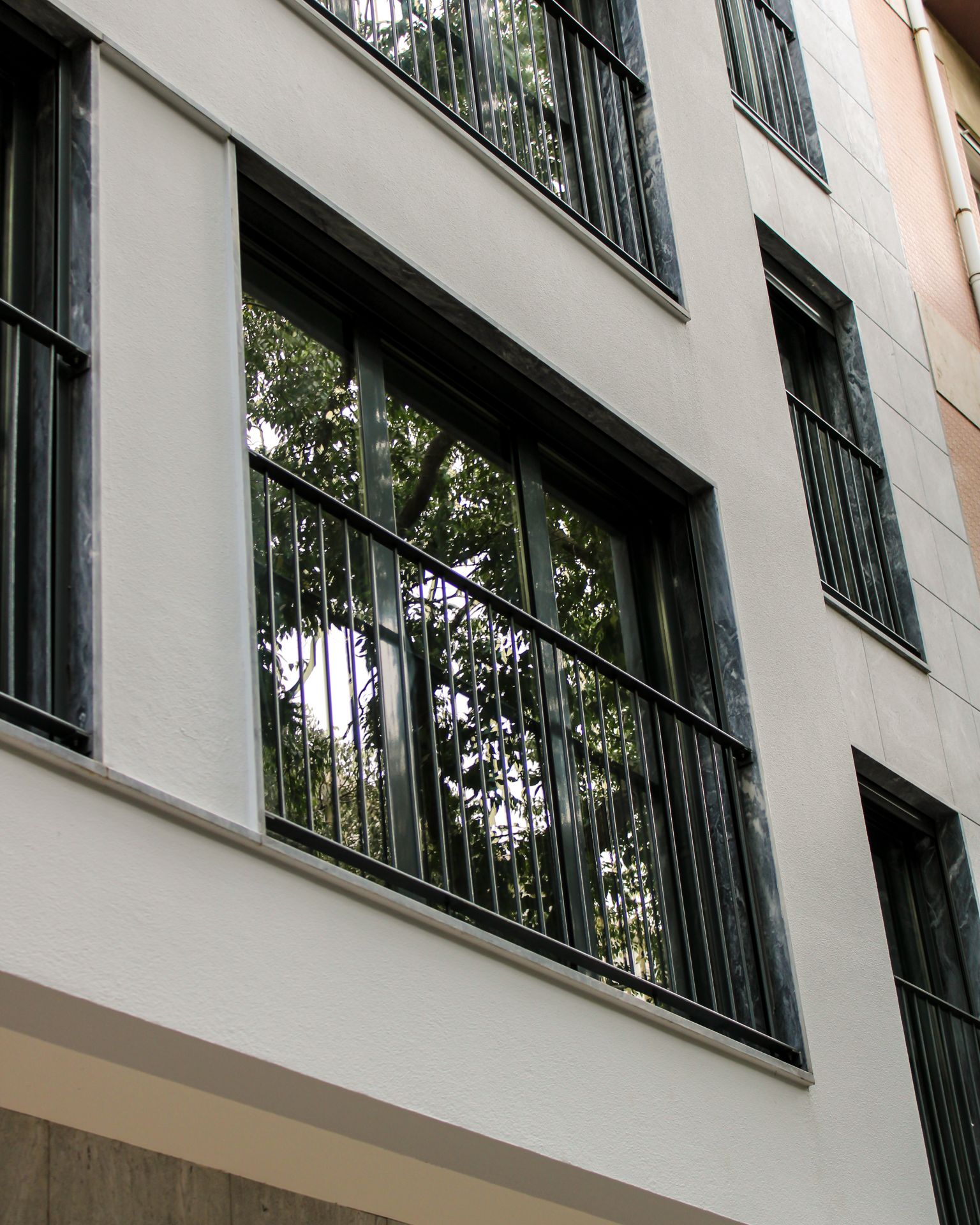 Fachada de edifício com janelas de alumínio preto e guardas