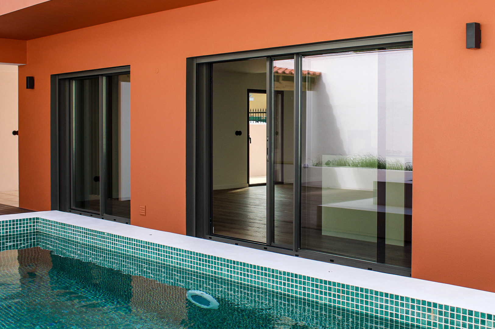 Detalhe exterior de portas de correr em alumínio antracite junto à piscina