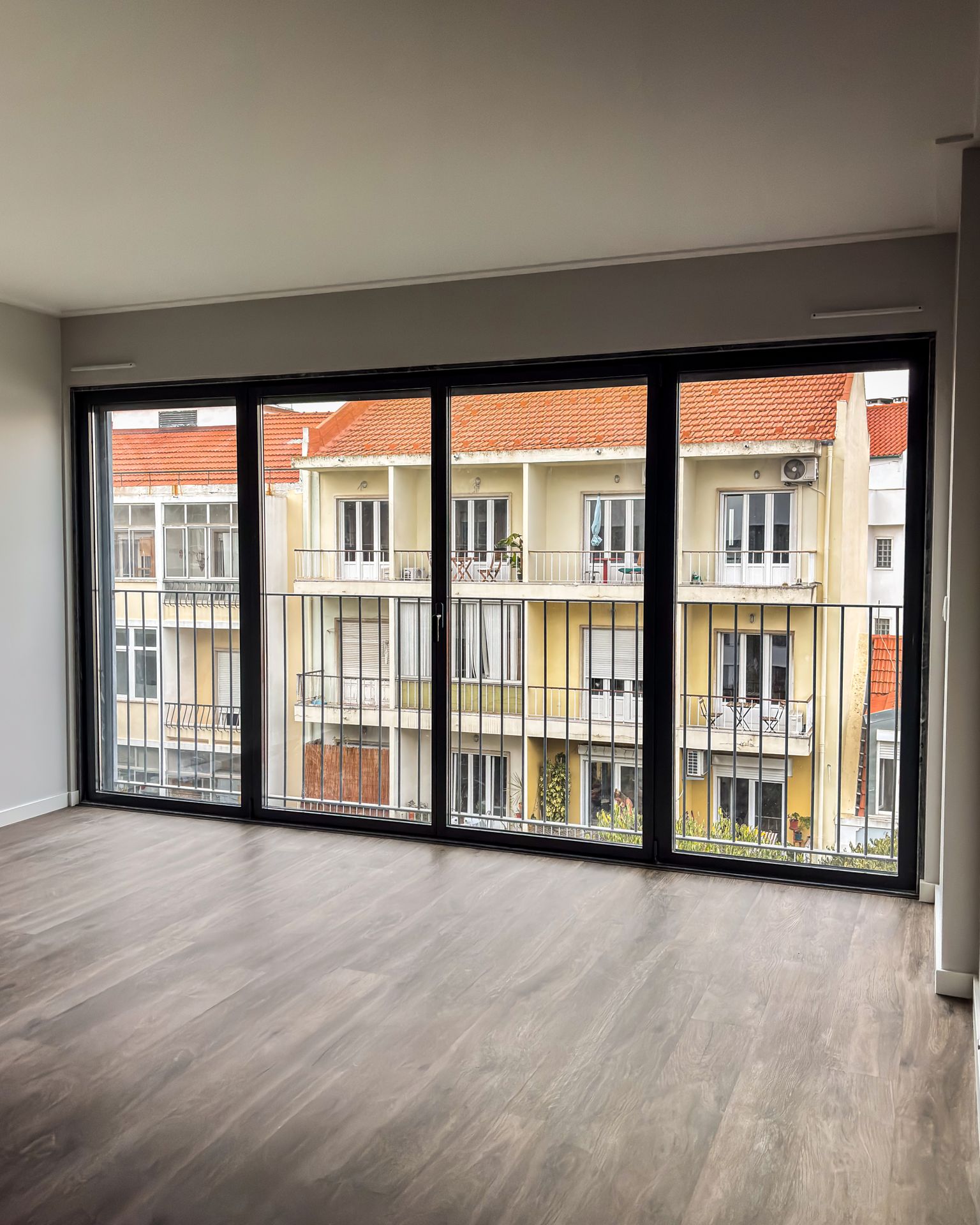 Sala com porta de correr em alumínio preto e vista sobre Lisboa